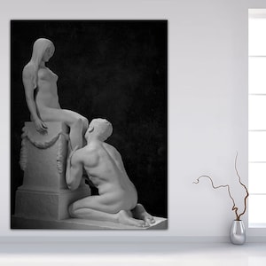 May include: Black and white photograph of a sculpture depicting a nude woman sitting on a pedestal with a man kneeling before her.