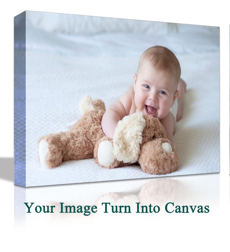 May include: A baby is lying on a white bedspread and smiling while holding a brown plush toy. The baby is wearing a white nappy and has a light brown complexion.