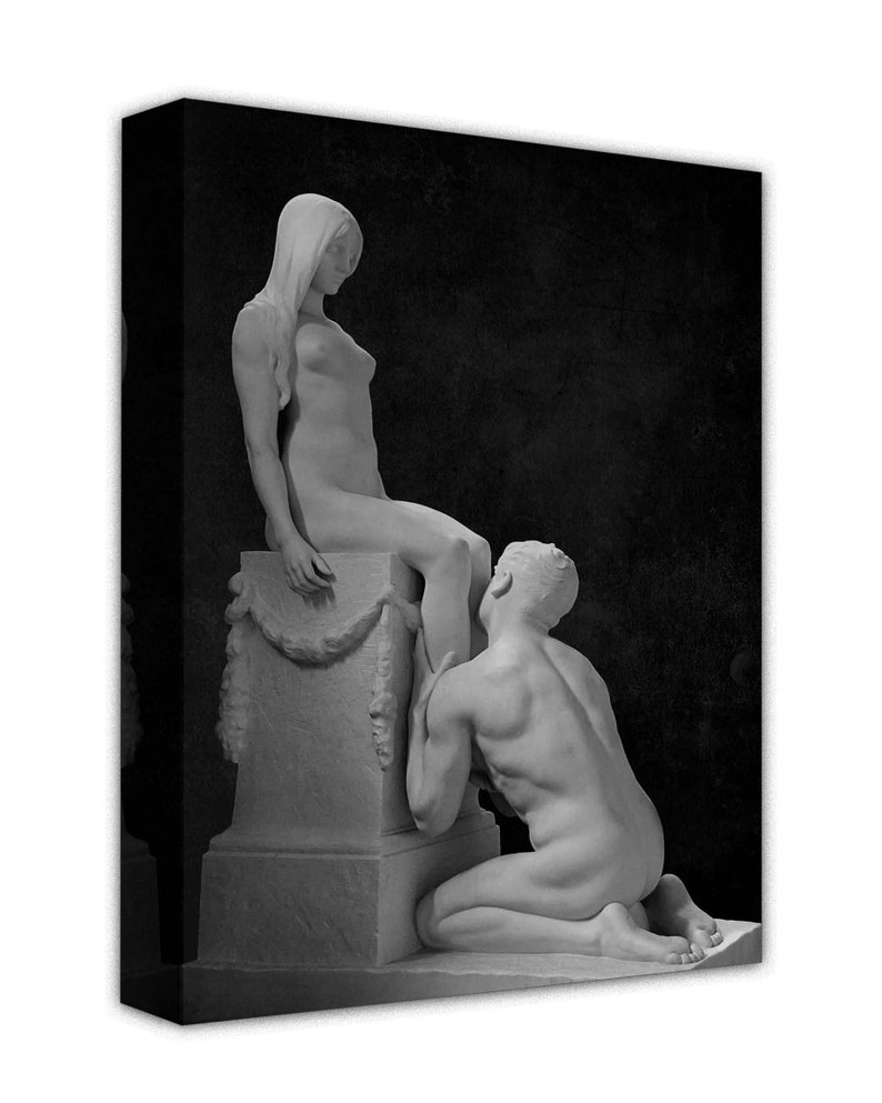 May include: Black and white photograph of a sculpture depicting a man kneeling and looking up at a woman standing on a pedestal.