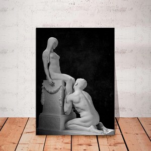 May include: Black and white photograph of two marble statues. The statues depict a woman sitting on a pedestal and a man kneeling before her.
