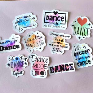 May include: A set of ten colorful dance-themed stickers with various inspirational quotes and designs. The stickers feature watercolor backgrounds and black text. Some of the quotes include "Dance Mode On", "Live a Little Dance a Lot", and "Dance with your heart and your feet will follow".