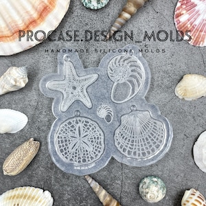 May include: Clear silicone mold with six different sea-themed designs: a starfish, a nautilus shell, a sand dollar, a clam shell, and two smaller shells. The mold is on a gray background with seashells.