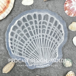 May include: A clear silicone mold shaped like a seashell with a detailed, intricate design. The mold is surrounded by seashells on a gray background. The text "PROCASE DESIGN MOLDS" and "HANDMADE SILICONE MOLDS" is visible on the mold.