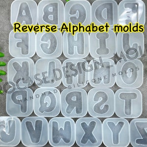 Peut inclure: Un ensemble de 26 moules en silicone transparents en forme de lettres de l'alphabet dans l'ordre inverse. Les moules sont disposés en rangées et sont étiquetés "Reverse Alphabet molds".
