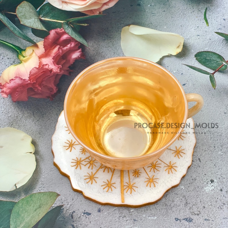May include: A gold-colored teacup sits on a white coaster with a gold dandelion design. The text "PROCASE.DESIGN.MOLDS HANDMADE SILICONE MOLDS" is printed on the coaster.