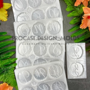 May include: Three white silicone molds for making resin crafts. Each mold has eight circular cavities with floral designs and letters. The molds are stacked on top of each other. The text on the molds reads "PROCASE.DESIGN_MOLDS", "HANDMADE SILICONE MOLDS", "PROCASE DESIGN MOLDS (Y-Z)", and "PROCASE DESIGN MOLDS (A-H)".