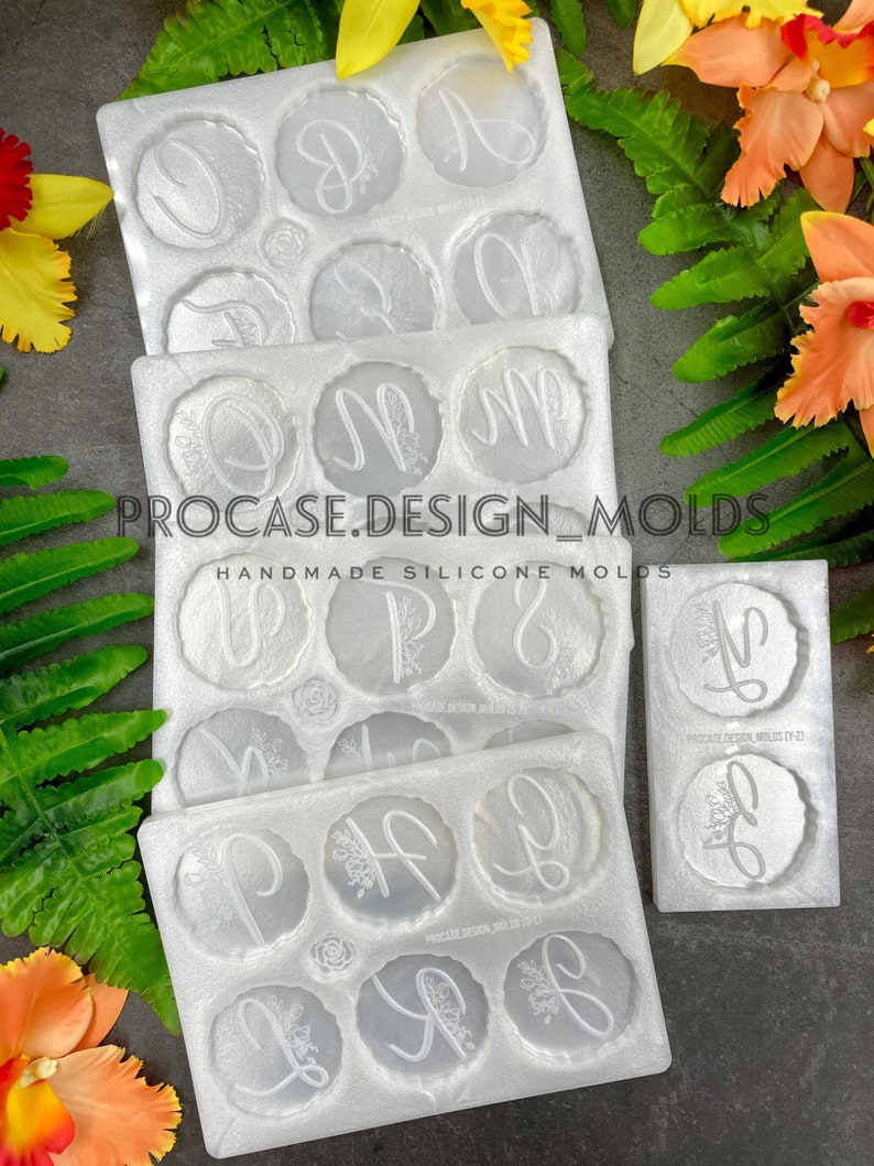 May include: Three white silicone molds for making resin crafts. Each mold has eight circular cavities with floral designs and letters. The molds are stacked on top of each other. The text on the molds reads "PROCASE.DESIGN_MOLDS", "HANDMADE SILICONE MOLDS", "PROCASE DESIGN MOLDS (Y-Z)", and "PROCASE DESIGN MOLDS (A-H)".