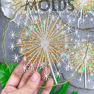 May include: A set of clear resin coasters with a gold glitter and white dandelion design. The coasters are handmade and have a slightly irregular shape. The text "PROCASE.DESIGN MOLDS HANDMADE SILICONE MOLDS" is visible in the image.