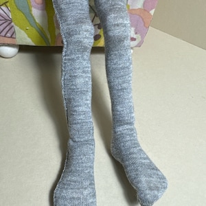 May include: Gray knit tights with a ribbed texture. The tights are worn on a pair of legs.