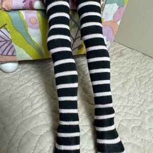 May include: Black and white striped knee-high socks with a pink stripe.