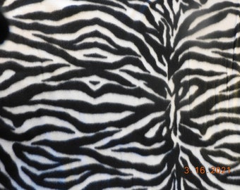 May include: Black and white zebra print fabric. The fabric has a soft, fuzzy texture.
