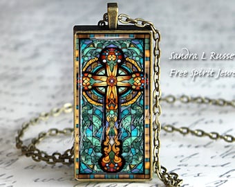 Peut inclure: Un collier avec un pendentif en forme de croix celtique en verre coloré. La croix est entourée d'un motif de vitrail coloré avec des nuances de bleu, vert, jaune et orange. Le collier est fait d'une chaîne en bronze.