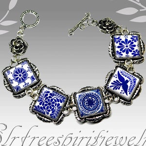 May include: A silver bracelet with blue and white ceramic tiles featuring floral and bird designs. The bracelet has a toggle clasp.