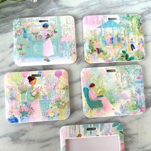 Może przedstawiać: Zestaw pięciu prostokątnych uchwytów na identyfikatory z zaokrąglonymi rogami, każdy z inną pastelową ilustracją kwiatową. Ilustracje przedstawiają sceny z ludźmi w ogrodach i kwiaciarniach. Każdy uchwyt ma małą szczelinę u góry.