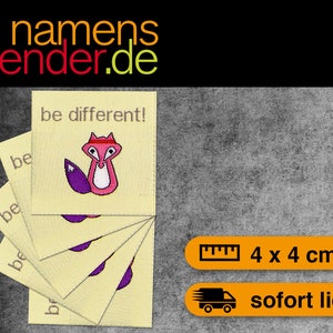 Könnte beinhalten: Fünf gelbe Stoff-Etiketten mit dem Text "be different!" und einem rosa Fuchs mit rotem Stirnband. Der Fuchs hat einen lila Schwanz. Die Etiketten sind 4 cm x 4 cm groß.