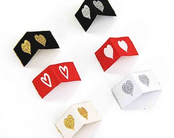 May include: Six fabric labels with two hearts each. The labels are in black, white, red, and cream with gold and silver hearts. The hearts are embroidered on the fabric.