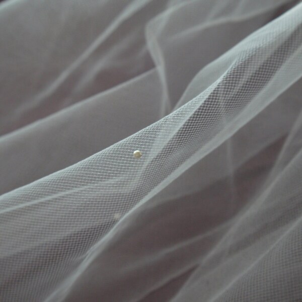 White delicate tulle single-layer veil with small pearls on a metal comb