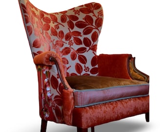 May include: A high-backed armchair with a red floral pattern on a cream background. The chair has a red velvet seat and back, with a brown cushion and wooden armrests. The chair's design is classic and elegant.