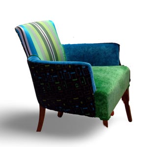 Op de afbeelding: Een kleurrijke fauteuil met een gestreepte rugleuning, een armleuning met geometrisch patroon en een groene zitting. De stoel heeft houten poten.