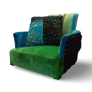 Op de afbeelding: Een groene, blauwe en zwarte fauteuil met een patchwork ontwerp. De fauteuil heeft twee kussens met geometrische patronen.