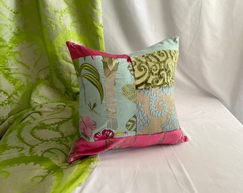 May include: A patchwork pillow with a pink, blue, and green floral design. The pillow is made of different fabrics and has a unique, handmade look.