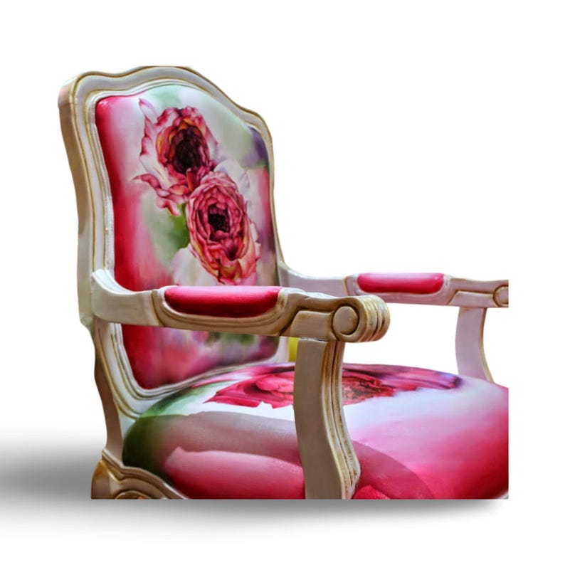 May include: A white and gold armchair with a pink and white floral patterned fabric upholstery. The chair has a high back and curved arms.