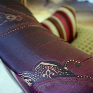 以下が含まれることがあります： パープルとブラウンの paisley 柄のファブリックのクローズアップ。ファブリックは柔らかく、高級感があり、上品な光沢があります。
