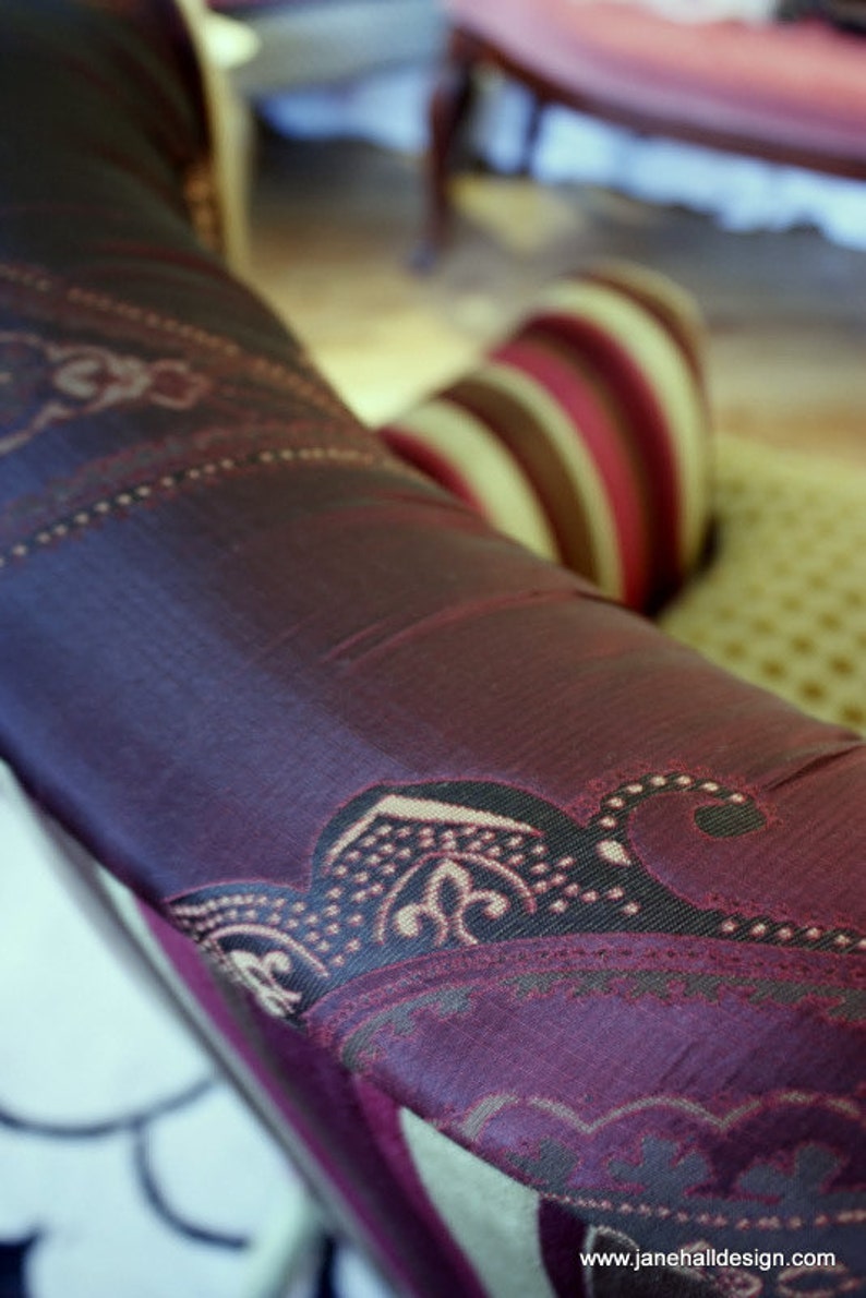 以下が含まれることがあります： パープルとブラウンの paisley 柄のファブリックのクローズアップ。ファブリックは柔らかく、高級感があり、上品な光沢があります。