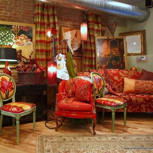 May include: A red and gold patterned sofa with pillows and two red chairs with floral designs. The chairs and sofa are in a room with red and gold patterned curtains and a rug.