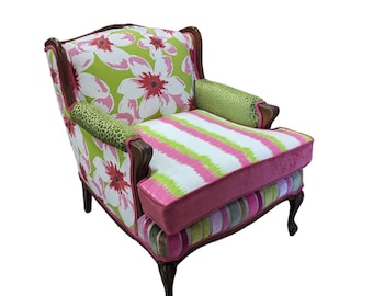 May include: A pink and green floral patterned armchair with a striped cushion. The chair has a wooden frame and carved legs.