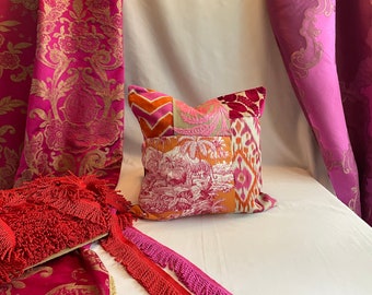 May include: A patchwork pillow with a pink, orange, and white floral pattern. The pillow is sitting on a white surface with pink and gold fabric in the background.