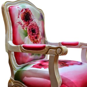 May include: A white and gold armchair with a floral patterned upholstery featuring pink roses. The chair has a high back and curved arms.