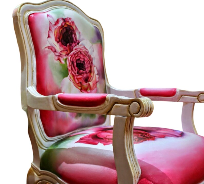 May include: A white and gold armchair with a floral patterned upholstery featuring pink roses. The chair has a high back and curved arms.