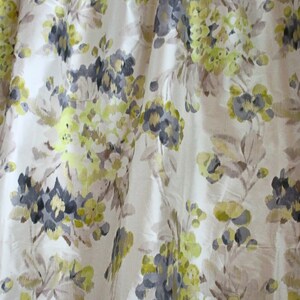 May include: A white fabric with a floral pattern in shades of gray, green, and brown. The flowers are stylized and abstract.