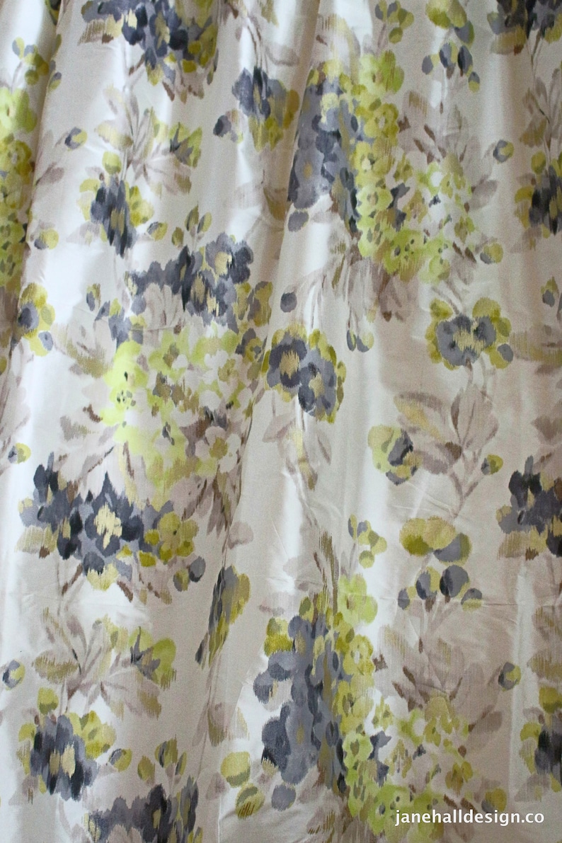 May include: A white fabric with a floral pattern in shades of gray, green, and brown. The flowers are stylized and abstract.