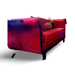 May include: A red velvet sofa with black wooden legs and arms. The sofa has a tufted back and is decorated with colorful throw pillows.