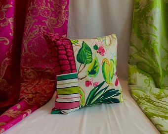 May include: A colorful throw pillow with a patchwork design featuring green, pink, and white floral patterns. The pillow is made of fabric and has a square shape.