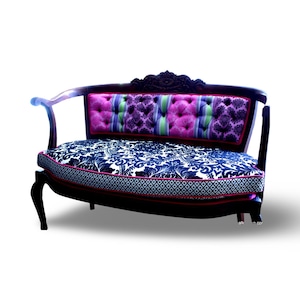 May include: A decorative loveseat with a dark wood frame. The backrest features a tufted design with pink, purple, and green stripes. The seat cushion has a blue and white floral pattern with a pink border. The loveseat has curved armrests.