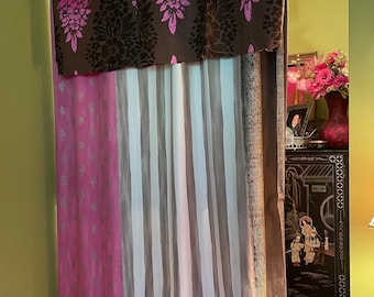 May include: A decorative curtain set with a brown valance featuring a floral pattern in shades of pink and black. The curtain panels below include a pink panel with silver leaf designs and a striped panel in white and grey.