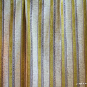 May include: Close-up of a striped fabric with alternating bands of yellow and beige. The fabric has a subtle texture and a slightly faded appearance.