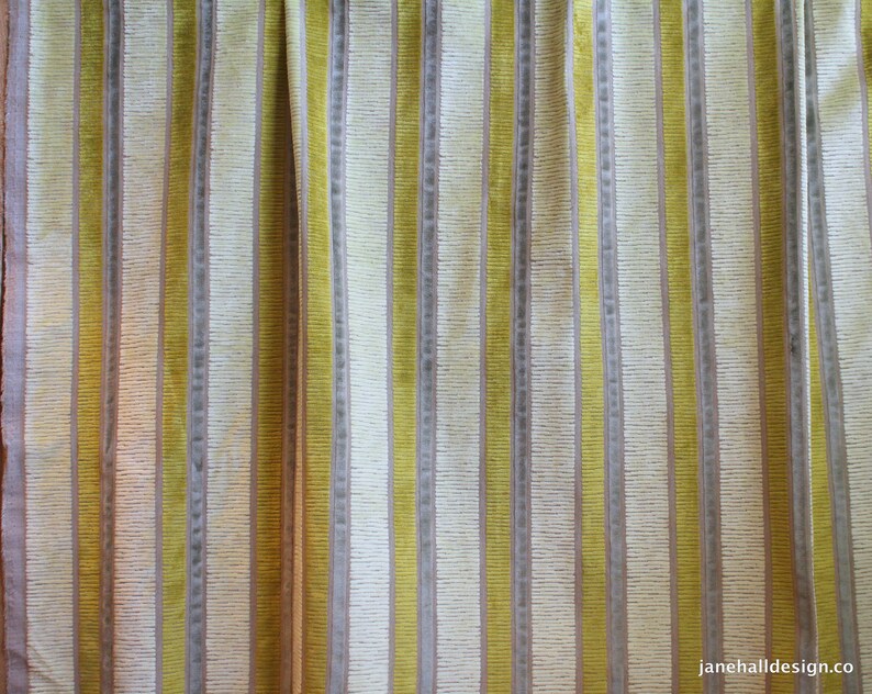 May include: Close-up of a striped fabric with alternating bands of yellow and beige. The fabric has a subtle texture and a slightly faded appearance.