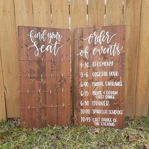May include: Two wooden signs with white lettering. The left sign says "find your seat" and has clothespins attached. The right sign says "order of events" and lists the wedding day schedule: 4:30 Ceremony, 5-6 Cocktail Hour, 6:00 Bridal Entrance, 6:15 Bride & Groom First Dance, 6:30 Dinner, 10:00 Sparkler Send Off, 10:45 Last Dance of the Evening.