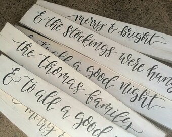 May include: White wooden signs with black calligraphy text. The signs read "Merry & Bright", "& the Stockings were hung", "To all a good night", and "& To all a good family".