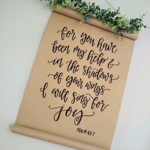 May include: A brown paper scroll with black calligraphy that reads "for you have been my help & in the shadows of your wings I will sing for joy" and "PSALM 63:7".