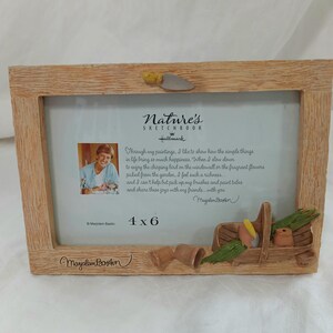May include: A rectangular picture frame with a light brown wood-grain texture. The top features a small trowel accent, while the bottom right corner displays a sculpted garden basket with vegetables. The frame includes a 4x6 insert with text.