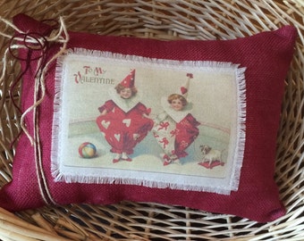 May include: Red burlap pillow with a white fabric panel featuring a vintage Valentine's Day card with two children dressed as clowns and the text "To My Valentine".