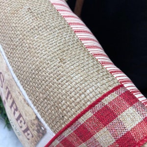 May include: A burlap pillow with a red and white striped fabric panel and a red and white gingham ribbon trim. The pillow has a vintage-style label that says "Christmas Tree".