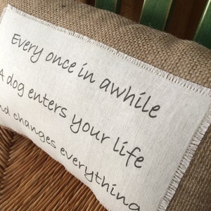 May include: A brown burlap pillow with a white fabric insert. The insert has the text "Every once in awhile a dog enters your life and changes everything" printed in black.