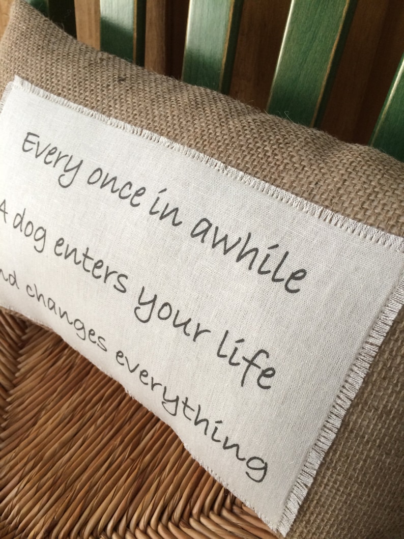 May include: A brown burlap pillow with a white fabric insert. The insert has the text "Every once in awhile a dog enters your life and changes everything" printed in black.