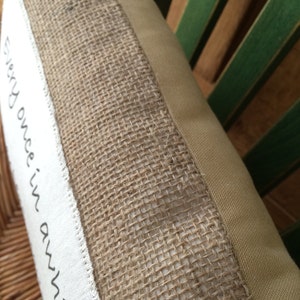 May include: A close-up of a beige pillow with a burlap trim and the text "Every once in awhile" printed on the front.